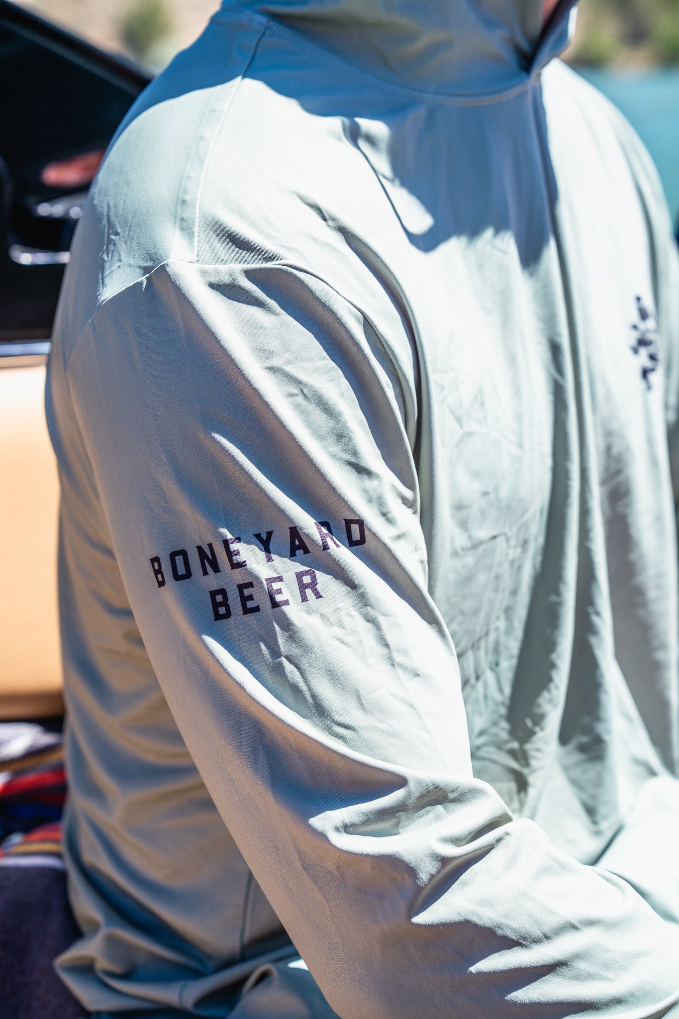 Light gray hooded sun shirt with 'Boneyard Beer' text on sleeve, worn by a person.