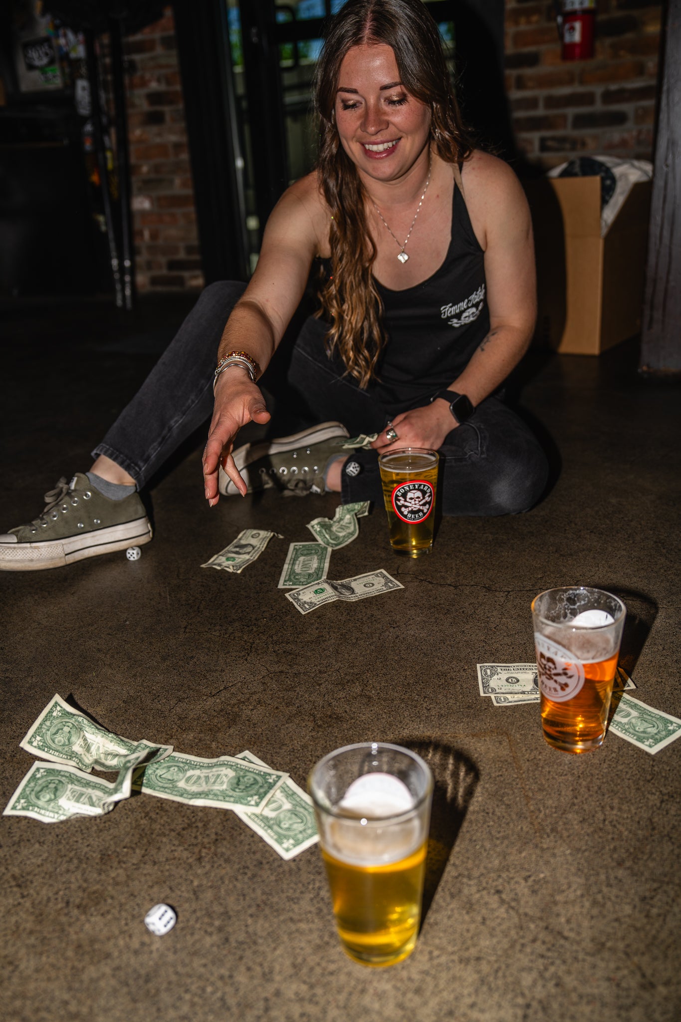 Woman sitting on the floor with beer glasses and money around her.
