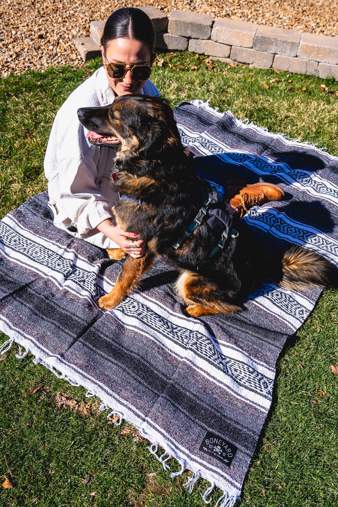 Woman holding a dog on a patterned blanket outdoors