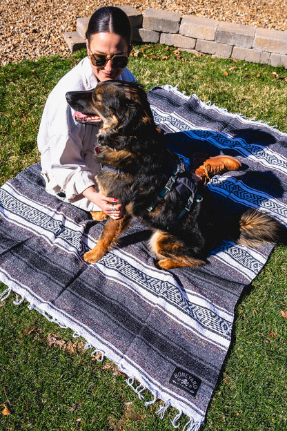 Woman holding a dog on a patterned blanket outdoors