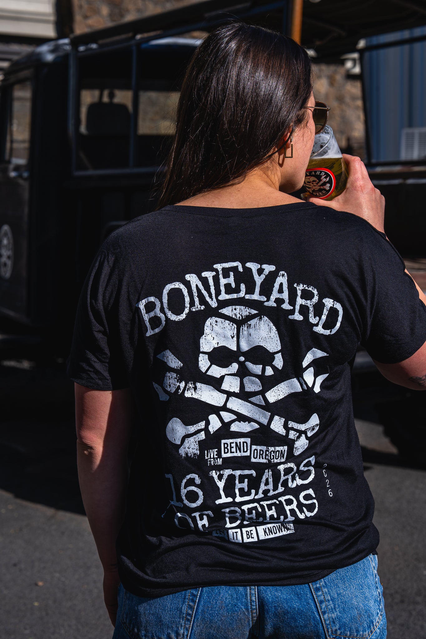 girl wearing 16 years of beers v neck from behind with boneyard logo