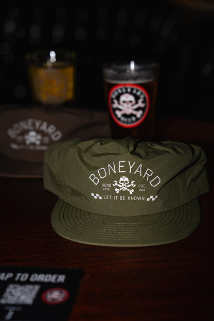 Green cap with 'Boneyard' logo on a dark background with candles and a sign.