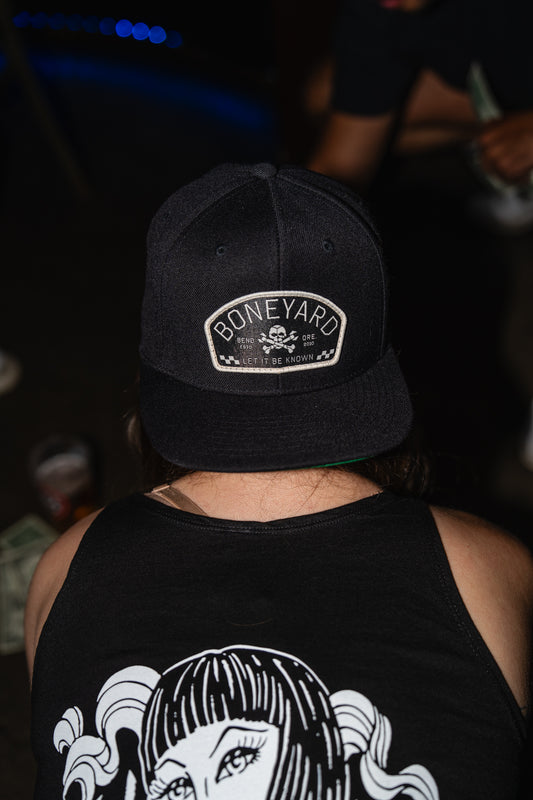 Person wearing a black cap with 'Boneyard' logo and black tank top with graphic design.