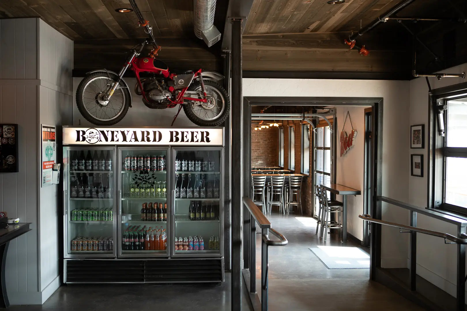 An interior photo of the Boneyard Pub. We see a motorcycle on top of a beer color and a look into a seating area.